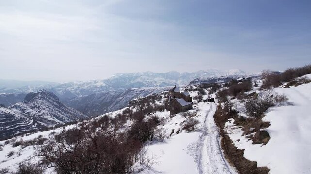 Drone footage of off-roading cars driving on snowy hills with a dried landscape