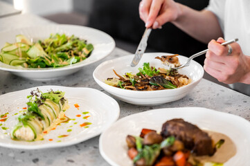 A dining scene featuring a person enjoying a gourmet meal, with several beautifully plated dishes, including risotto and vegetables. The modern table setting enhances the dining experience.
