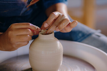 Close-up of a Latina woman’s hands shaping a ceramic piece in her workshop. The image captures effort, focus, and handcrafted detail.
