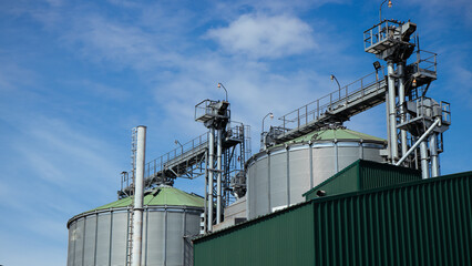 Grain elevator standing tall against a clear blue sky, industrial agricultural facility in bright daylight.