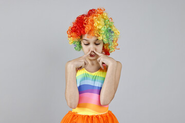 Cute girl dressed like clown on grey background. Surprise party