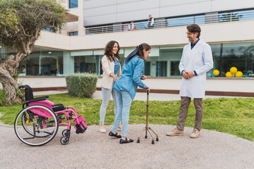 Young woman with cerebral palsy walking with support - Young woman leaves wheelchair and walks...