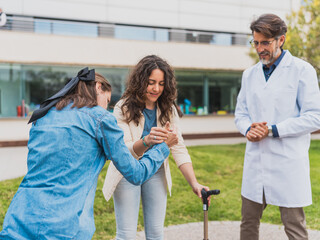 Doctor supervises young woman with cerebral palsy standing up - Doctor observes as caregiver helps young woman with cerebral palsy stand up - Concept of cerebral palsy.