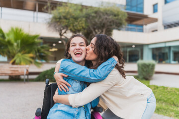 Caregiver hugs and kisses young woman with cerebral palsy - Emotional moment between caregiver and young woman in wheelchair - Concept of cerebral palsy.