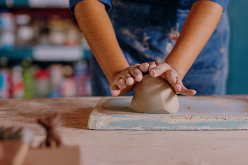 Mexican woman, 24, prepares clay in her artisan workshop before molding. Scene captures the beginning of the ceramic-making process and focus on her technique.

