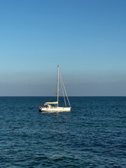 Obraz premium A small sailing ship on the sea at the horizon