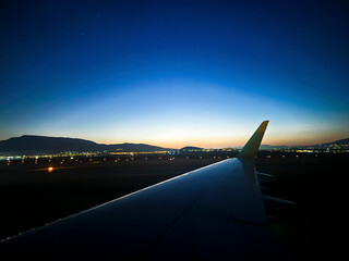 Airplane wing from the window during takeoff at sunset