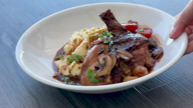 Serving a Plate of Chicken Coq au vin with Mashed Potatoes and Mushrooms 