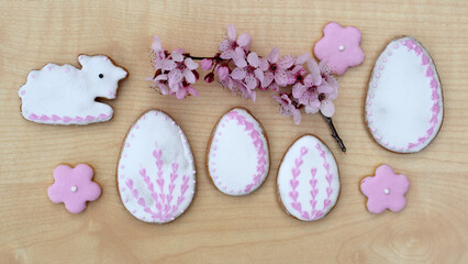 Easter gingerbread cookies of various shapes, decorated with white and pink icing, with spring blooming twig