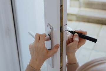 One young man draws marks on the door frame using a marker.
