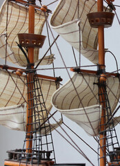 Web of rigging ropes over sails on masts background. Old sailing ship model with wooden masts and...