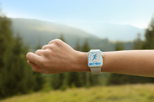 Woman checking smart watch with step counting app in wilderness, closeup