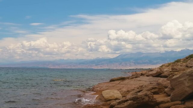 This 4K footage captures the rugged rocky coast of Assyk Kul Lake, with cloudy skies and majestic mountains towering in the background. Perfect for nature lovers and scenic beauty enthusiasts.