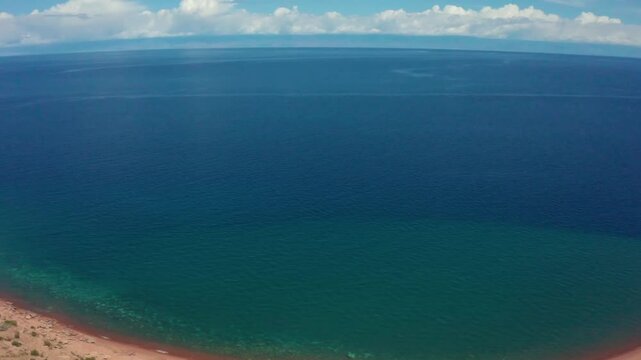 Drone footage showcasing the crystal-clear, blueish-green waters of Assyk Kul Lake, revealing the natural beauty of this stunning destination in Kyrgyzstan.