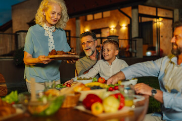 Family enjoying dinner together on a summer evening in their backyard