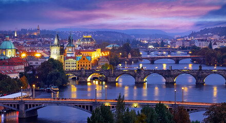 Prague Czech Republic. Panoramic view at Charles Bridge. Majestic medieval architecture of old town on river Vltava. Picturesque nighttime landscape panorama with blue sky and evening illumination.