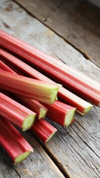 Fresh Raw Rhubarb Stalks Lying on Weathered Wooden Surface, Close-up Arrangement for Cooking