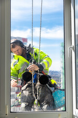 Professional Window Cleaner Performing High-Rise Building Maintenance While Harnessed, Ensuring...
