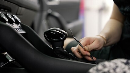 Close-up of professional car detailer cleaning interior of vehicle with specialized tool, focusing on removing dust and dirt from gear stick area
