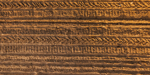 view from above on surface of texture of dry road with tractor tire tracks in countryside