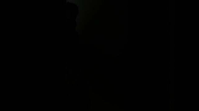 Horizontal video. Mature man with beard in blue jeans denim jacket checks into hotel. Tourist enters dark room with red suitcase. Concept of trip, travel, tourism, arrival, relax, rest, check in
