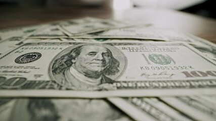 Male hands sliding stack of 100 dollar bills across wooden table and pulling it back. Close-up shot of US currency gesture. Concept of financial decision, money offer, bribe, negotiation. - Powered by Adobe