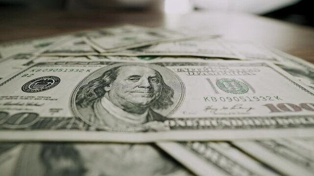 Male hands sliding stack of 100 dollar bills across wooden table and pulling it back. Close-up shot of US currency gesture. Concept of financial decision, money offer, bribe, negotiation.