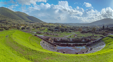 Archaeological site of Ancient Messene, UNESCO World Heritage, Peloponnese, Greece, Ancient Greek theater ruins in a green landscape under clouds
