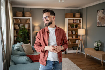 Fototapeta premium Happy man smiling and enjoying his modern apartment living room