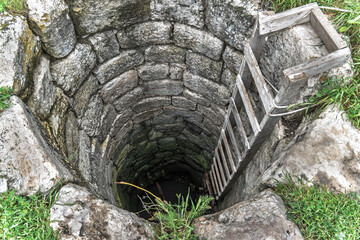 Old Stone Water Well with Wooden Ladder