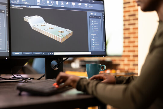 Black female developer designing industrial machinery using creative engineering software. Closeup on african american engineer seated at desk, developing digital clamps and tools on a desktop pc.