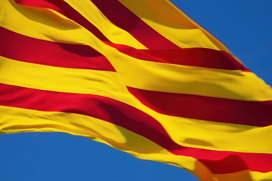 Close-up of Catalan flag waving in the wind against blue sky