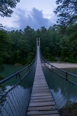 Fototapeta premium Wooden Suspension Bridge Over Lake in Forest