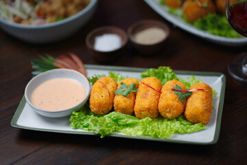 Delicious Crispy Croquettes with Dipping Sauce on a Leafy Garnish