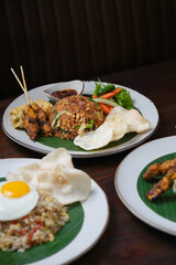 Indonesian Fried Rice with Satay, Fried Egg, and Fresh Vegetables on Banana Leaf