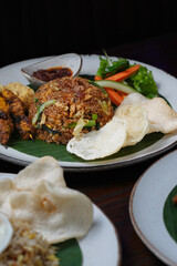  Indonesian Fried Rice with Satay, Fried Egg, and Fresh Vegetables on Banana Leaf