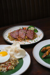 Grilled Sliced Beef over Fried Rice with Steamed Vegetables and Fresh Garnishes