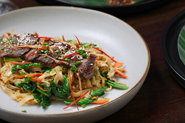 Stir-Fried Beef Noodles with Fresh Vegetables and Sesame Garnish