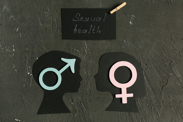 Silhouettes of boy's and girl's heads with male and female symbols and card with text SEXUAL HEALTH...