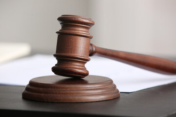 Judge's gavel with documents on black table in office, closeup