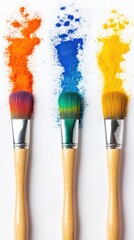 Fototapeta premium Three art brushes, adorned with vibrant colored pigments, against a white background.