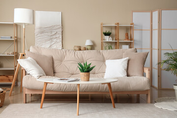 Interior of beautiful living room with comfortable sofa, coffee table, houseplant and pillows