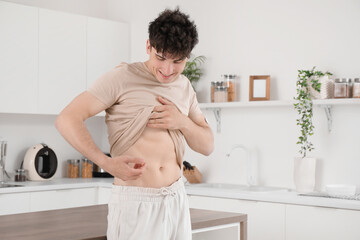 Diabetic young man giving himself insulin injection in kitchen