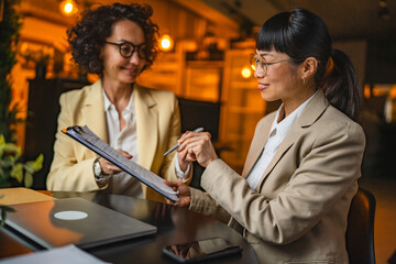 caucasian businesswoman give to japanese female client contract to sign