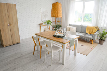 Interior of light room with dining table and sofa