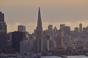 The sun sinks lower in the sky, casting shadows on the skyline of San Francisco