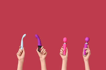 Female hands with different vibrators on red background