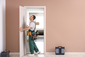 Male worker with tools examining door at home