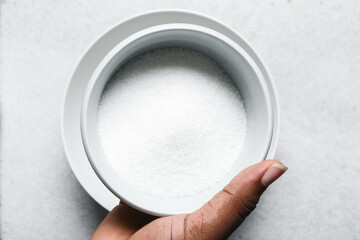 Overhead view of white sugar in a white plate, top view of granulated sugar in a plate
