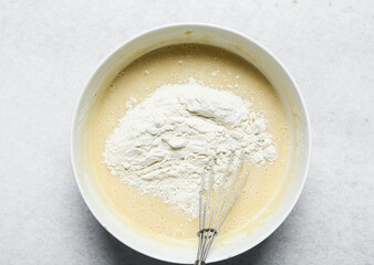 Overhead view of flour being mixed into cake batter, top view of vanilla cake batter being mixed, process of making vanilla cake